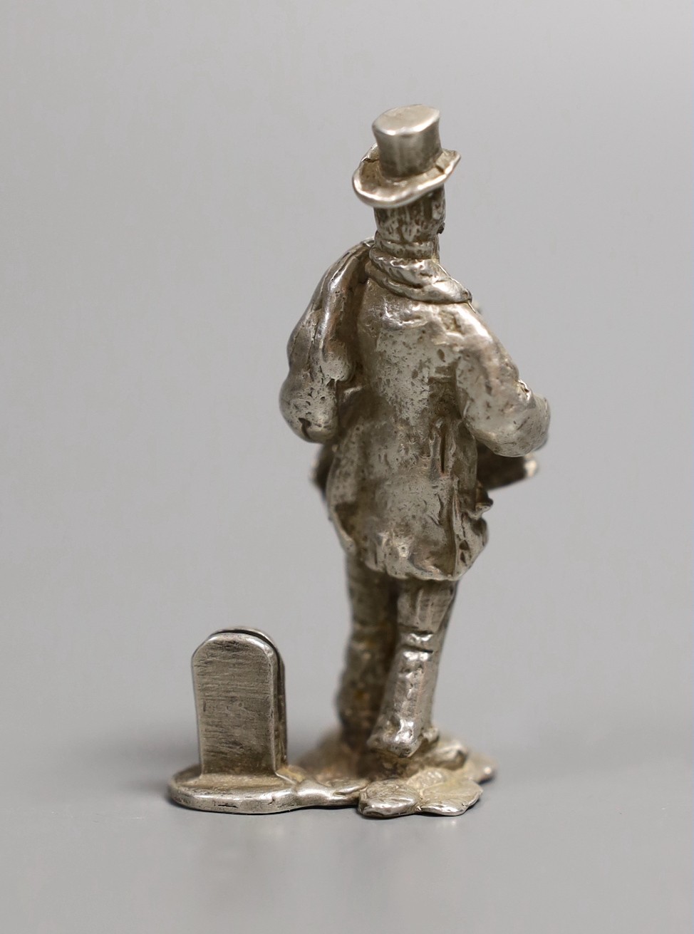 A modern novelty silver menu holder modelled as a traveller by a milestone, by Thomas Charles Jarvis, London, 1971, 57mm, 53 grams.